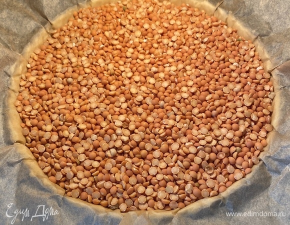 В это время разогреть духовку до 170°C. В форму с тестом положить лист пергамента, сверху насыпать груз из любой крупы и запекать 15 мин. Через 15 минут убрать груз и пергамент, выпекать еще 15 минут.