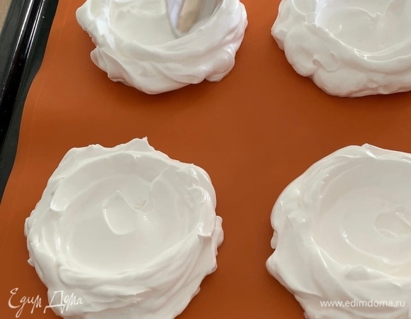 На противень положите силиконовый коврик. Разделите безе на 4 равные части. Выкладывайте безе гнездами с небольшим углублением в центре на расстоянии друг от друга.