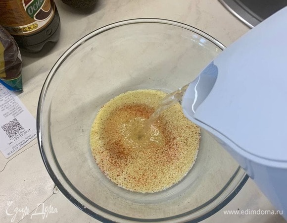 Выкладываем кускус в глубокую миску, добавляем в него соль, перец и заливаем кипяченой водой из чайника, добавляем туда же немного подсолнечного масла, накрываем крышкой и оставляем завариваться.