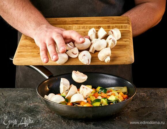 Нарежьте грибы кусочками и добавьте к овощам. Обжаривайте около 15 минут.
