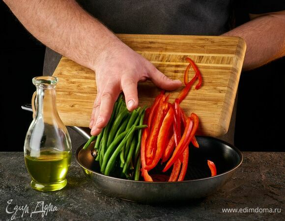 Добавьте в сковороду стручковую фасоль и болгарский перец, нарезанный соломкой. Обжаривайте примерно 2 минуты.