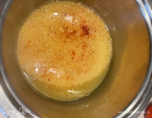 Засыпаем кускус в небольшую кастрюлю или миску, добавляем тертую цедру лимона, паприку, оливковое масло. Заливаем кипятком, накрываем крышкой и оставляем на 10 минут.