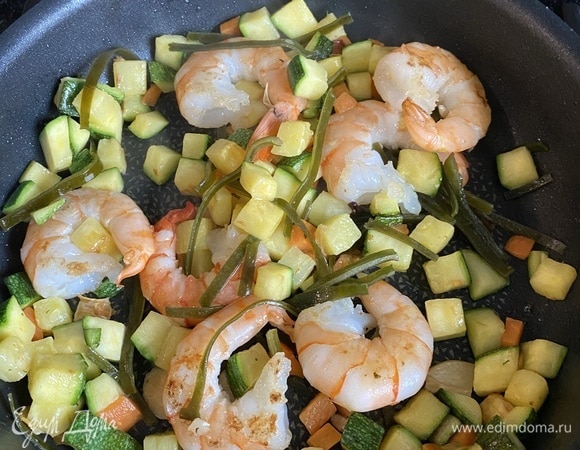 Соединяем в одной сковороде овощи, креветки и морскую капусту.