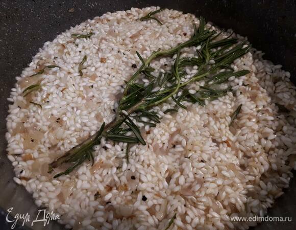 Убавьте огонь. Влейте 150 мл белого вина и оставьте выпариваться. Затем влейте половник бульона и оставьте выпариваться. Вообще это принцип ризотто: бульон добавляют небольшими порциями, и каждый раз ждут, когда жидкость выпарится — и так до готовности риса. Между добавлением бульона рис нужно помешивать.