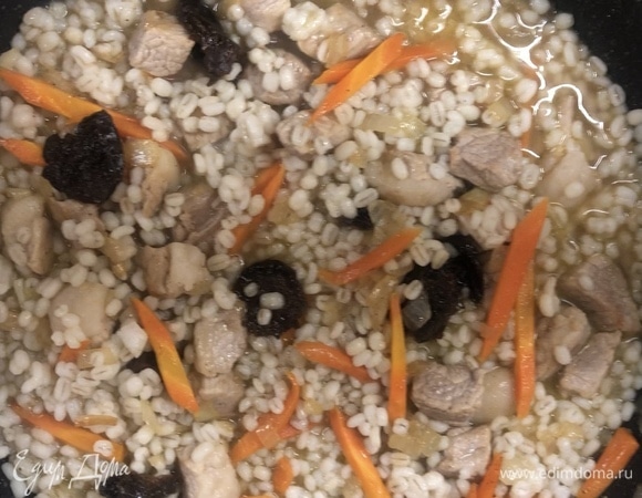 Добавьте перловку, немного обжарьте, слейте воду с чернослива и тушите до готовности.