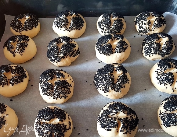 Яйцо слегка взбить. Каждую булочку сначала окунуть в яйцо, а потом — кунжут. Ножницами сделать крестообразные надрезы. накрыть булочки полотенцем и оставить на 40 минут.