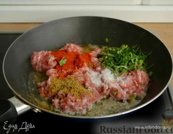 В сковороде растопите половину сливочного масла и выложите туда свиной фарш. Добавьте петрушку, сахар, паприку, итальянские травы, соль и черный перец.