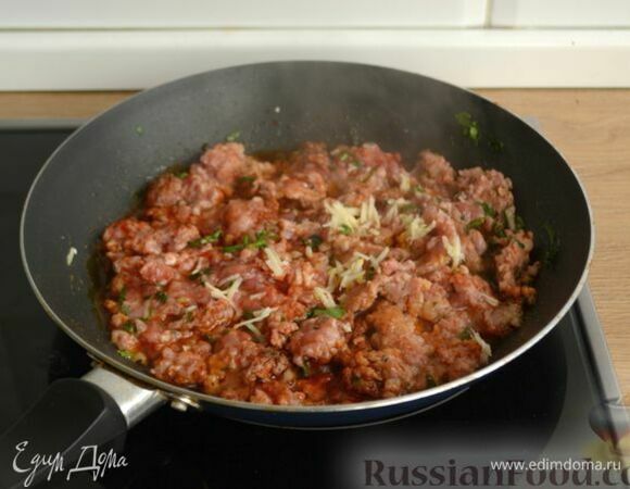 Перемешайте фарш с зеленью и специями. Затем туда же на мелкой терке натрите очищенный зубчик чеснока (или выдавите через пресс). Обжаривайте 5–6 минут, периодически разбивая деревянной лопаткой комочки фарша.