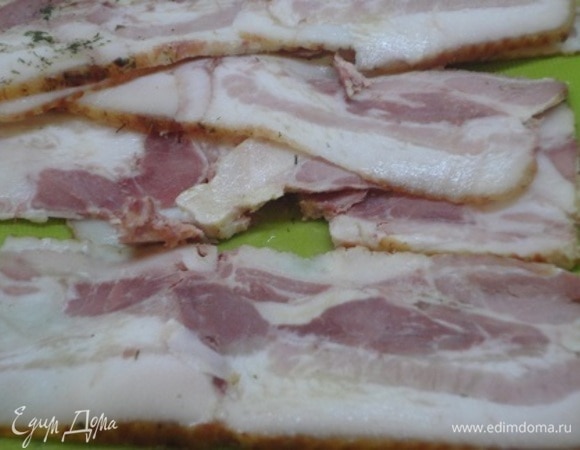 Полосками бекона выстилаем форму для запекания, выкладываем половину фарша, делая небольшую «канавку» вдоль, заполняем брынзой с овощами и зеленью. Накрываем второй половиной фарша и закрываем сверху оставшимися свободными полосками бекона.