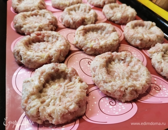 Из фарша сформировать колобки и выложить их на противень. Предварительно застелить бумагой для выпечки или ковриком. Донышком от стакана сделать углубление. Чтобы фарш не прилипал к стакану, смочить его водой.