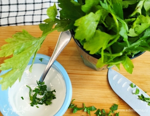 В густую сметану (можно заменить на творожный сыр) кладем измельченную петрушку. Затем нарезаем сочный помидор, а рыбу отделяем от костей.