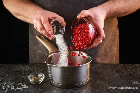 Приготовьте соус. Ягоды красной смородины промойте и снимите с веточек. Выложите в сотейник, всыпьте сахарный песок.