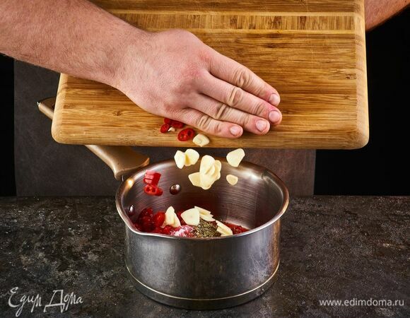 Добавьте чеснок, нарезанный слайсами и перец чили.