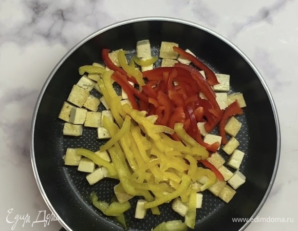 Чеснок мелко нарезаем и отправляем на сковороду с оливковым маслом. Обжариваем пару минут и убираем чеснок, он нам еще понадобится. Добавляем в сковороду тофу, нарезанный кубиками. Обжариваем со всех сторон до золотистой корочки. Болгарский перец нарезаем соломкой, отправляем в сковороду к тофу и готовим до размягчениях.