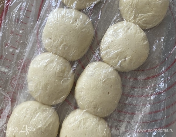 Спустя время подошедшее тесто обмять, разделить на 8 больших или 16 маленьких частей, скатать каждую в шарик, накрыть пленкой, отставить на 20 минут.