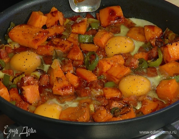 Яйца разбить в сковороду с колбасой и овощами, посолить, поперчить и запекать в разогретой духовке 3–4 минуты.