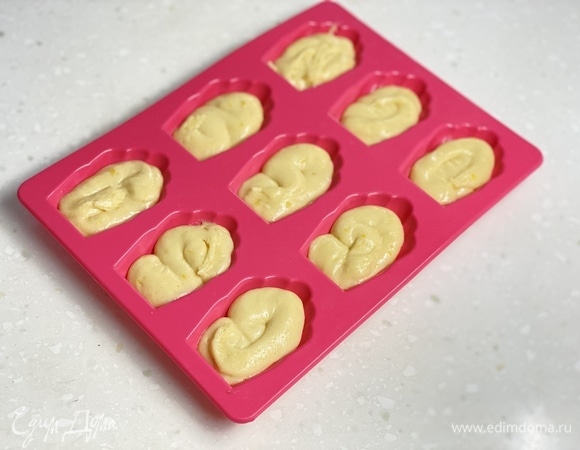 Через сутки наполнить из мешка формы примерно наполовину и выпекать при 200–210°C около 15 минут. Выпекать в несколько заходов, каждый раз убирая тесто в холодильник.