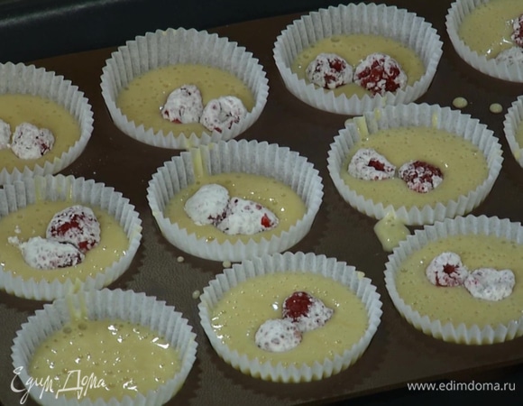 Смешать с крахмалом 150 г замороженной малины, поместить в каждую формочку с тестом по 2–3 ягоды и ложкой утопить ягоды в тесте. 