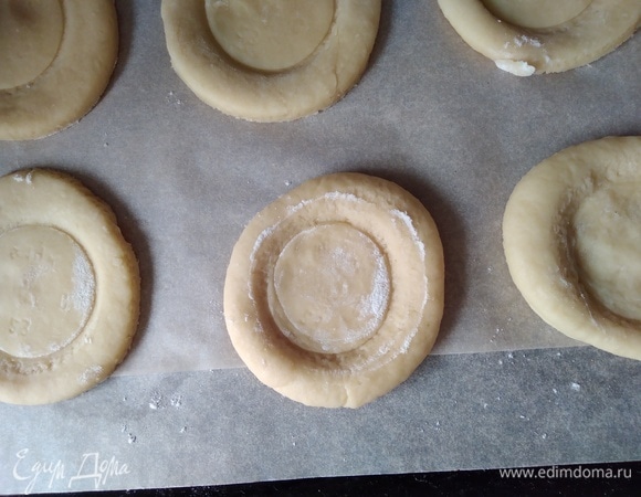 Раскатать тесто (стол немного посыпать мукой) до толщины 2 см. Вырезать выемкой круги около 8 см. Стаканом поменьше придавить середину заготовки.