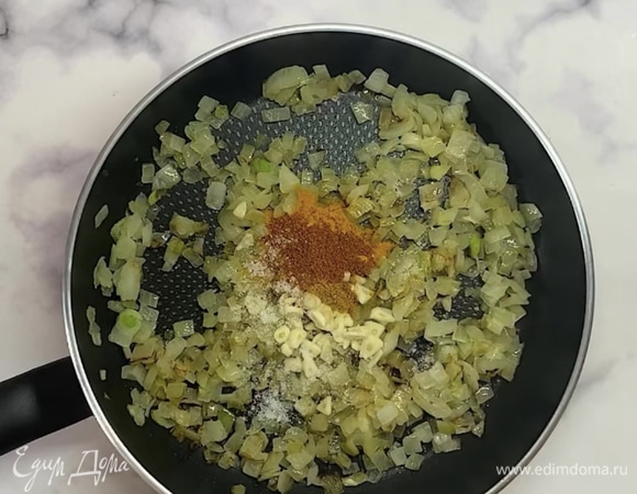 Лук мелко нарезаем и отправляем на сковороду с оливковым маслом. Обжариваем пару минут до золотистого цвета. Добавляем нарезанный чеснок и специи: карри, куркуму, острый перец и соль. Обжариваем минуту.
