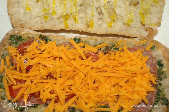 Сыр чеддер натереть на крупной терке. Выкладываем сыр сверху на помидоры. Верхнюю часть чиабатты немного смазываем горчичным маслом и накрываем начинку.