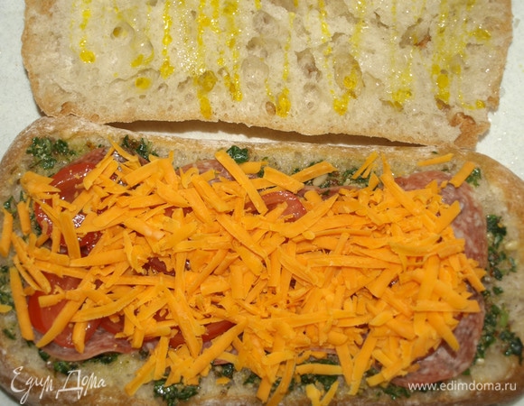 Сыр чеддер натереть на крупной терке. Выкладываем сыр сверху на помидоры. Верхнюю часть чиабатты немного смазываем горчичным маслом и накрываем начинку.