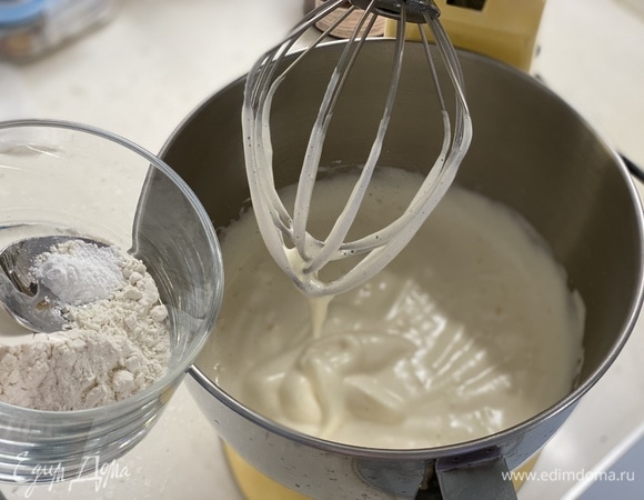 Яйца взбить с сахаром, пока масса не увеличится в объеме втрое. Смешать муку, крахмал и разрыхлитель. В три приема аккуратно вмешать в яичную смесь движениями снизу вверх.