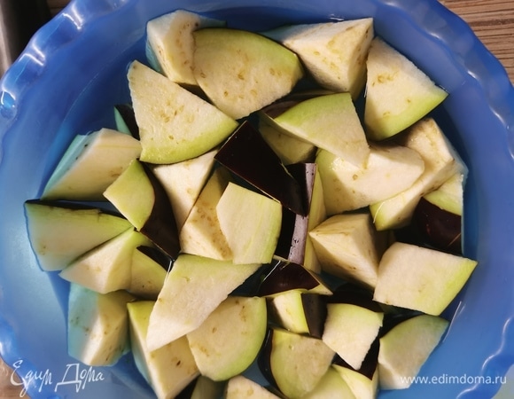 Баклажаны выложить в миску с холодной подсоленной водой. Перемешать ложкой, пусть баклажаны немного пропитаются водой. Откинуть на дуршлаг, чтобы стекла лишняя влага.