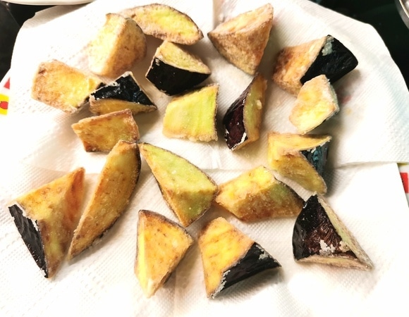 Шумовкой достать готовые баклажаны и выложить на салфетку, чтобы стекло лишнее масло.