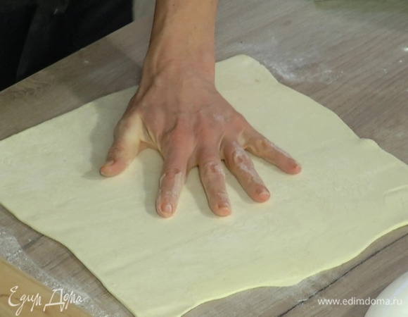 Тесто разморозить и слегка раскатать на присыпанной мукой рабочей поверхности, затем выложить в круглую форму для выпечки, сформировать бортики, лишнее тесто срезать.