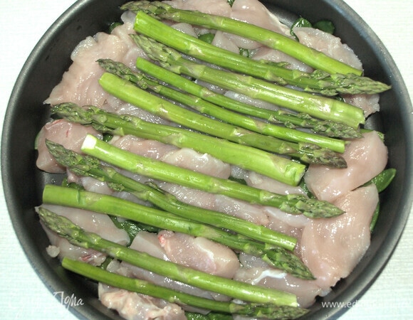 На дно формы для запекания выкладываем горошек, сверху — куриное филе и спаржу.