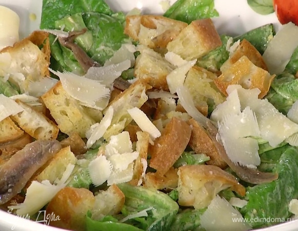 Листья салата смешать с заправкой, добавить гренки, анчоусы, сыр, все перемешать.