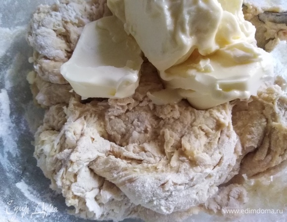 Постепенно всыпать муку, замешивая тесто. Добавить размягченное сливочное масло.