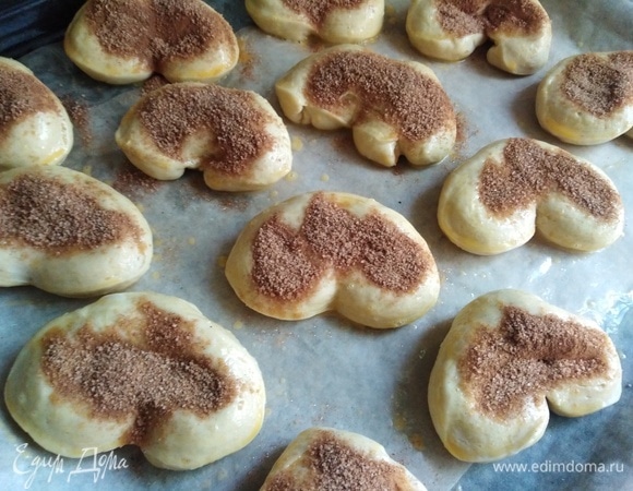 Выложить заготовки на противень, застеленный пекарской бумагой. Бумагу смазать растительным маслом. 1 ч. л. молотой корицы смешать с 1,5 ст. л. сахарного песка. Плюшки смазать желтком и посыпать приготовленной смесью из сахара и корицы.