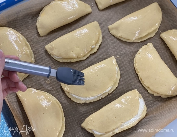 Второй половиной лепешки накрыть начинку. Смазать каждый сочник яйцом с помощью кисточки. Выпекать около 20 минут при 180°C.
