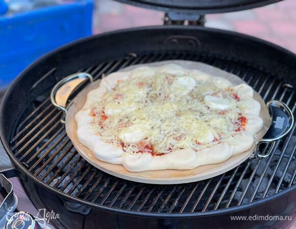 Хорошо разогрейте гриль и не забудьте поместить на решетку специальный плоский камень. Именно на него нужно будет аккуратно переложить пиццу вместе с пергаментом для запекания. Температура внутри гриля должна составлять 300–350°C. Пицца выпекается 7–9 минут при закрытой крышке. 