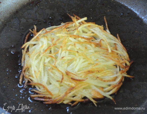 Картофель натрите на терке, промойте в дуршлаге и дайте стечь воде. На той же сковороде, где жарили сосиски с беконом, обжарьте порционно картофель. По желанию слегка посолите и поперчите.