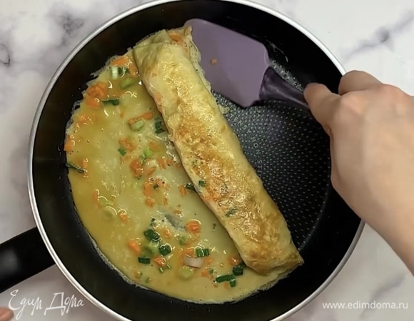 Когда омлет немного схватился, сворачиваем в рулет. Отодвигаем остальную часть рулета в сторону и к открытому краю добавляем еще немного яичной массы. Продолжаем, пока не закончится яичная масса.