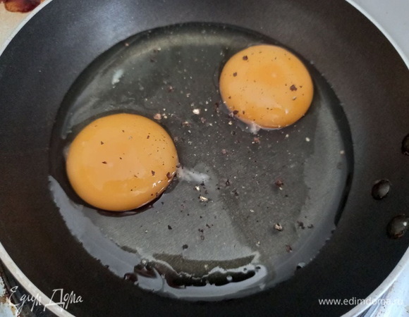 На сковороду наливаем подсолнечное масло, разбиваем яйца, солим и перчим. Мне было удобнее обжарить яйца порционно (по два в небольшой сковороде), но можно обжарить сразу все в одной большой. 