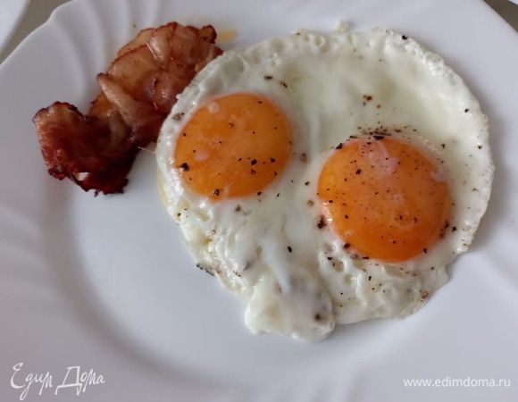 К бекону на тарелку выкладываем готовые яйца.