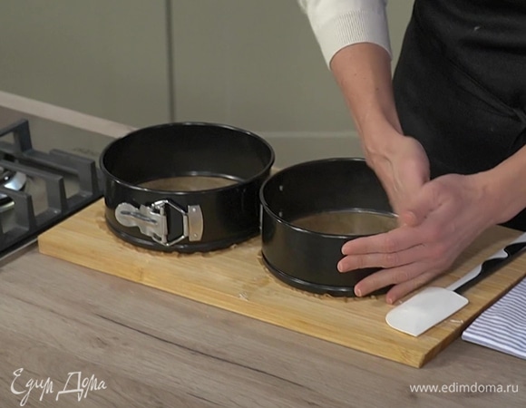 Две круглые разъемные формы застелить бумагой для выпечки, смазать оставшимся сливочным маслом и равномерно выложить тесто.