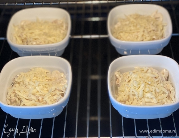 Сыр натереть на средней терке. Смешать в отдельной миске кальмары, шампиньоны, 2/3 тертого сыра и соус, хорошо перемешать ложкой. Разложить по формочкам — кокотницам для запекания жюльена. Сверху посыпать оставшейся 1/3 частью сыра.