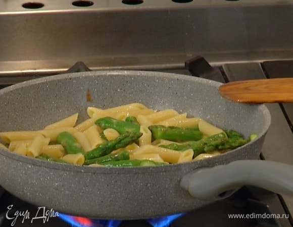 Воду из макарон слить и сохранить, выложить пенне в сковороду со спаржей и прогревать все около минуты, доливая по необходимости оставленную воду, затем добавить сливочное масло и, помешивая, немного обжарить.