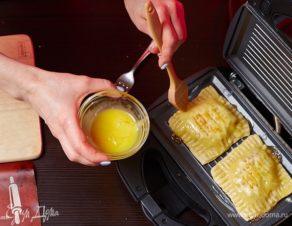 Разогрейте гриль, мультипекарь или сковороду. Выложите заготовки. Смажьте верх желтком.