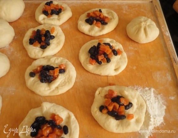 Каждую заготовку раскатать в лепешку (гладкая сторона должна быть снизу), выложить творожную начинку и начинку из сухофруктов. Тщательно скрепить концы, перевернуть швом вниз, прокрутить будущую булочку на столе, чтобы получился красивый шарик.