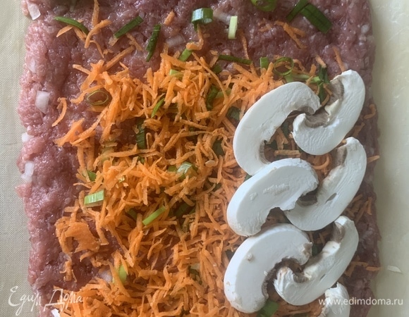 Фарш выкладываем не очень тонким слоем на коврик/пергамент, сверху — лук с морковью, раскладываем грибы, можно посыпать укропом по желанию.