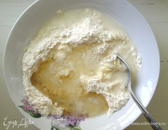 Влить растительное масло и горячую воду. Сначала вымешивать ложкой, а потом — руками.