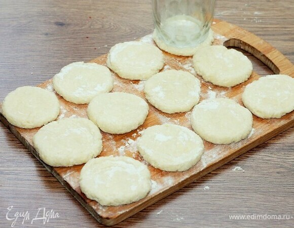 На припыленной мукой поверхности разложите шарики и надавите на них рукой или стаканом. Должна получиться круглая лепешка.