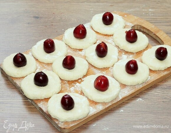 В середину лепешек положите по одной ягоде. Края теста заверните наверх, осторожно закрыв ягоды.