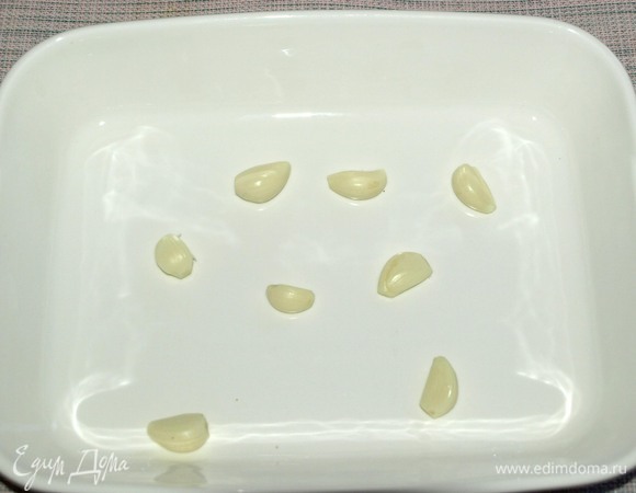 Берем глубокую форму для запекания. Чеснок очищаем и выкладываем целые зубчики на дно формы.